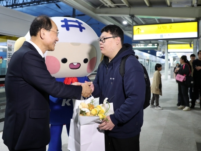 이성해 국가철도공단 이사장(왼쪽)이 2일 홍성역에서 첫 열차 탑승객에게 꽃다발과 기념품을 증정하고 있다./국가철도공단